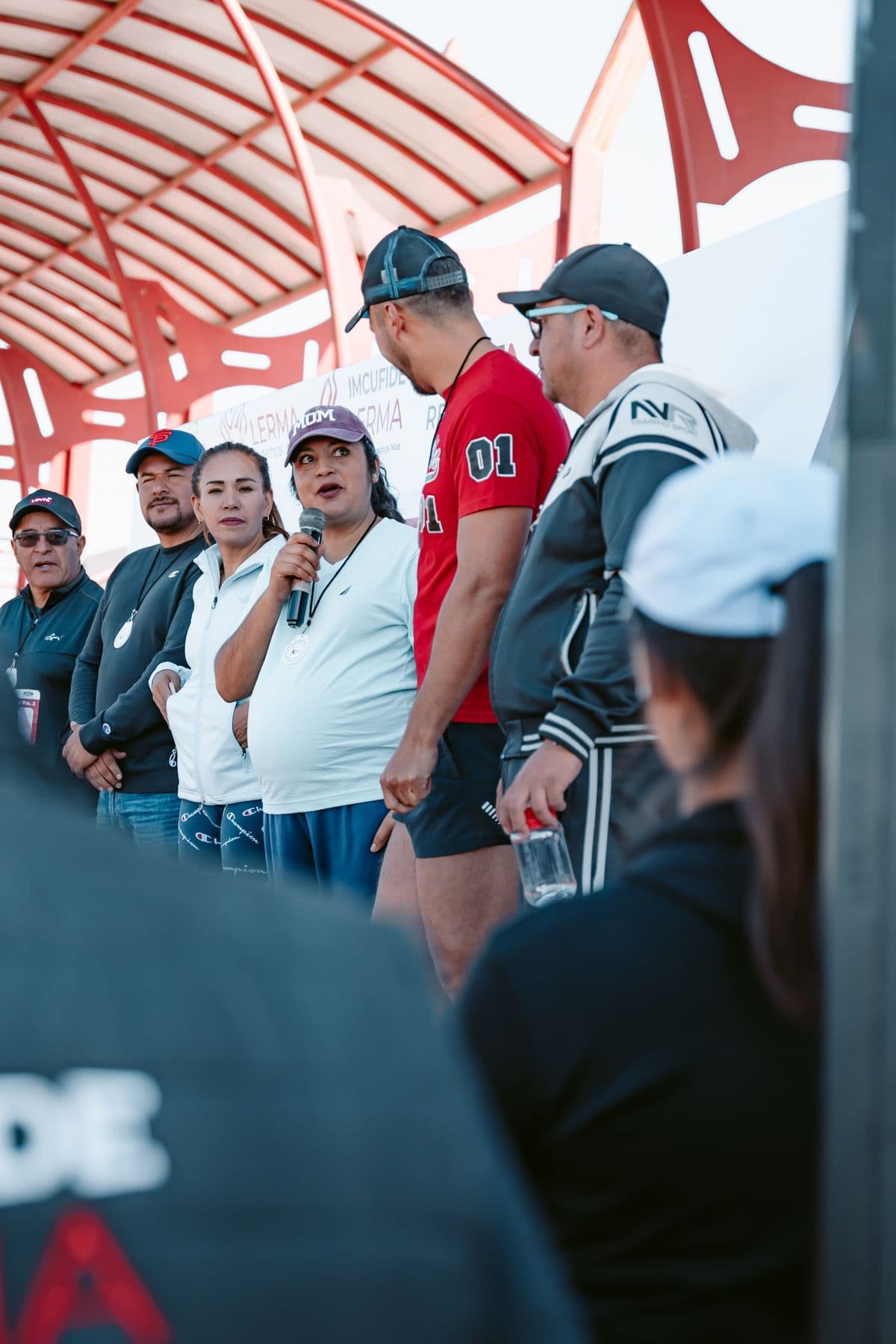 Mulher fala ao microfone para moradores em um evento comunitário